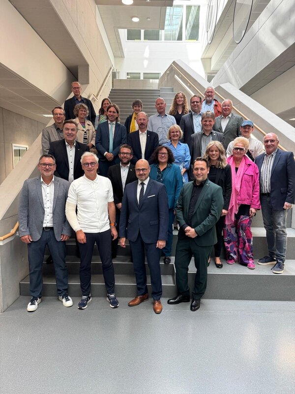 Erkunden die neue Albert-Einstein-Schule, die die Fertigstellung des 2. Bauabschnitts markiert: Stellvertretender Schulleiter Carmelo Calabrese, Landrat Dr. Christoph Schnaudigel und Oberb&uuml;rgermeister Johannes Arnold (1. Reihe von links nach rechts) gemei