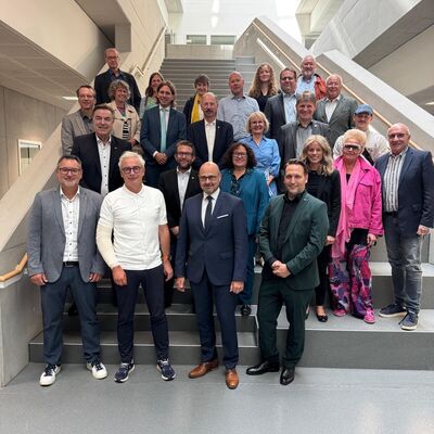 Bild vergr&ouml;&szlig;ern: Erkunden die neue Albert-Einstein-Schule, die die Fertigstellung des 2. Bauabschnitts markiert: Stellvertretender Schulleiter Carmelo Calabrese, Landrat Dr. Christoph Schnaudigel und Oberb�rgermeister Johannes Arnold (1. Reihe von links nach rechts) gemeinsam mit Vertreterinnen und Vertretern aus Politik, Wirtschaft und Schule.