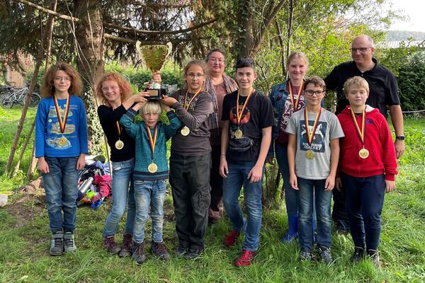 Acht Kinder der Falken-Gruppe der Agnus-Jugend Weingarten nehmen gemeinsam mit den Vorsitzenden Loubna Oberwinkler und Oliver Regelmann den Siegerpokal entgegen.