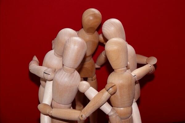 Bild vergrößern: Eine Gruppe aus Holzfiguren, die sich im Arm halten